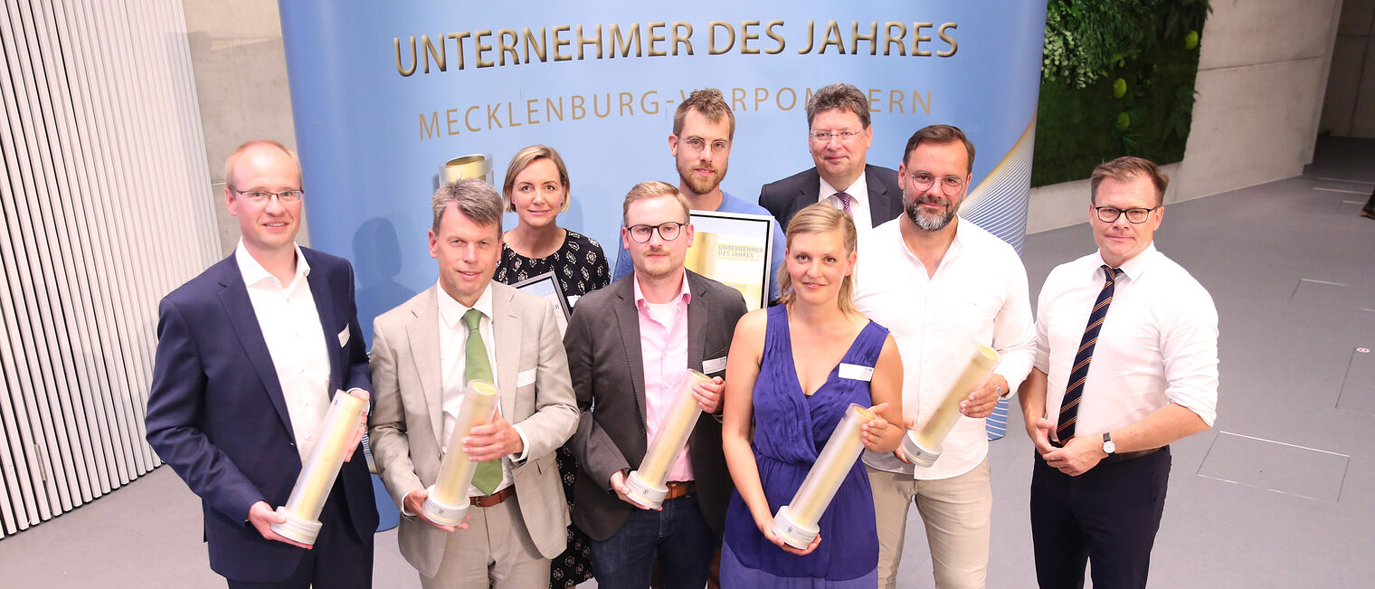 Erste Reihe: Jan-Christoph Block - Dockweiler AG - Neustadt - (Preisträger Fachkräftesicherung und Familienfreundlichkeit), Caspar Baumgart WEMAG AG - Schwerin (Preisträger Nachhaltigkeit), Jens Wiencke - MALIE - Mecklenburgisches Matratzenwerk GmbH - Warin (Preisträger Unternehmensentwicklung), Luzi Graf - MAXLUZI GmbH - Wustrow - (Preisträger: Sonderpreis - Fair, regional und kreativ gestaltet Zukunft), Eike Sadewater - Scheelehof Betreibergesellschaft mbH - Stralsund (Preisträger Unternehmerpersönlichkeit), Carsten Schneider - Beauftragter der Bundesregierung für Ostdeutschland; Zweite Reihe: Zara Gottschalk - Dockweiler AG, Max Strack - MAXLUZI GmbH, Reinhard Meyer - Wirtschaftsminister M-V Erste Reihe: Jan-Christoph Block - Dockweiler AG - Neustadt - (Preisträger Fachkräftesicherung und Familienfreundlichkeit), Caspar Baumgart WEMAG AG - Schwerin (Preisträger Nachhaltigkeit), Jens Wiencke - MALIE - Mecklenburgisches Matratzenwerk GmbH - Warin (Preisträger Unternehmensentwicklung), Luzi Graf - MAXLUZI GmbH - Wustrow - (Preisträger: Sonderpreis - Fair, regional und kreativ gestaltet Zukunft), Eike Sadewater - Scheelehof Betreibergesellschaft mbH - Stralsund (Preisträger Unternehmerpersönlichkeit), Carsten Schneider - Beauftragter der Bundesregierung für Ostdeutschland; Zweite Reihe: Zara Gottschalk - Dockweiler AG, Max Strack - MAXLUZI GmbH, Reinhard Meyer - Wirtschaftsminister M-V
